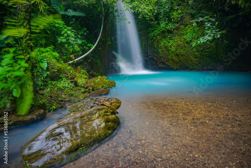 Curug Cipondok of Subang west Java Indonesia. Jungle waterfall cascade in tropical rainforest with rock and turquoise blue pond.  photo