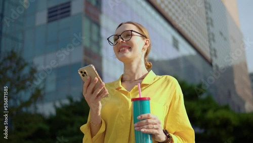 Office worker in vibrant yellow outfit using phone looking down at smartphone screen then lift uo eyes and show toothy smile happy to see boyfriend photo