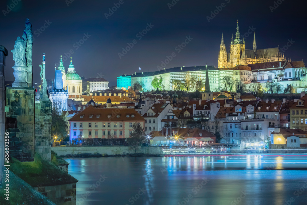Charles bridge and Vltava river at night with blurred boat movement, Prague