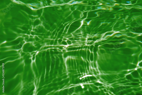 Defocus blurred transparent blue colored clear calm water surface texture with splash, bubble. Shining blue water ripple background. Surface of water in swimming pool. Blue bubble water shining.