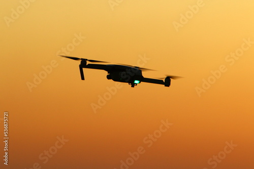 A quadrocopter with a photo camera flies over the sea. © shimon