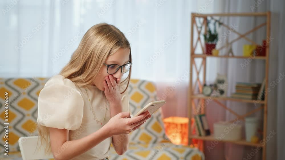 Teenage girl opens mouth in surprise looking at phone Teenage girl opens mouth in surprise looking at phone