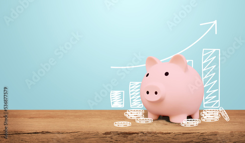 Piggy bank on a wooden table with blue background. saving money and invest concept.