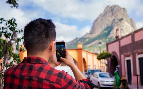Unrecognizable young tourist taking pictures of the Peña de Bernal. Concept of tourism