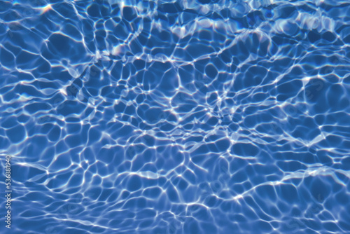 Defocus blurred transparent blue colored clear calm water surface texture with splash  bubble. Shining blue water ripple background. Surface of water in swimming pool. Blue bubble water shining.