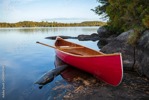 Φωτογραφία Red wood canoe on rocky shore of a Boundary Waters lake in morning light during