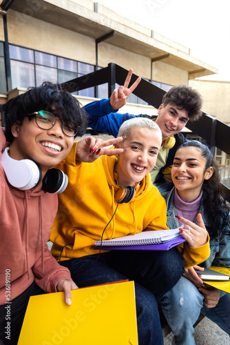 Multiracial gen z friends taking selfie with phone outside university building. College students having fun. Vertical. photo