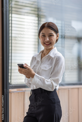 Happy millennial hispanic teen girl checking social media holding smartphone at home. Smiling young asian woman using mobile phone app playing game, shopping online, ordering delivery relax on desk. © David