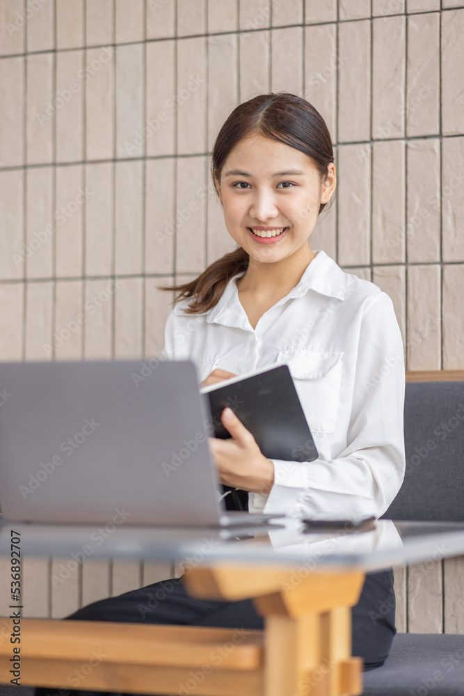 Young Asian lady studying online from home, reading a book and using laptop pc, sitting on the coffee shop, free space. E-learning, web-based education concept Young Asian lady studying online from home, reading a book and using laptop pc, sitting on the coffee shop, free space. E-learning, web-based education concept