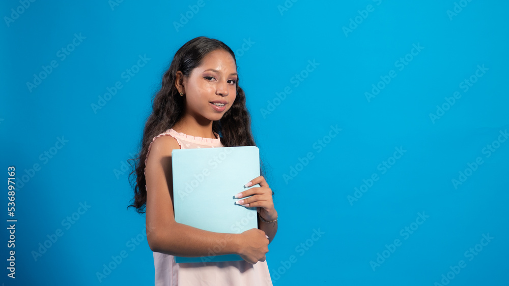 Niña con fondo azul usando una carpeta, día de escuela Niña con fondo azul usando una carpeta, día de escuela