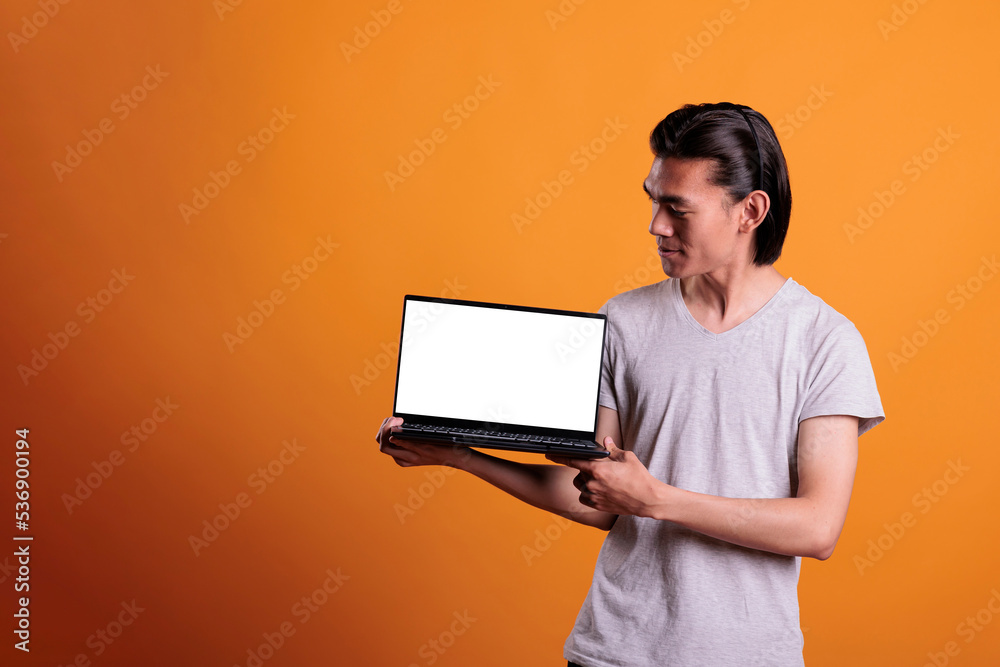 Confident asian man showing laptop with white blank screen, software advertising mock up. Smiling teenager holding portable computer with empty display, monitor with place for text Confident asian man showing laptop with white blank screen, software advertising mock up. Smiling teenager holding portable computer with empty display, monitor with place for text
