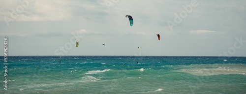Group of tourists kitesurfing at the beach during summer