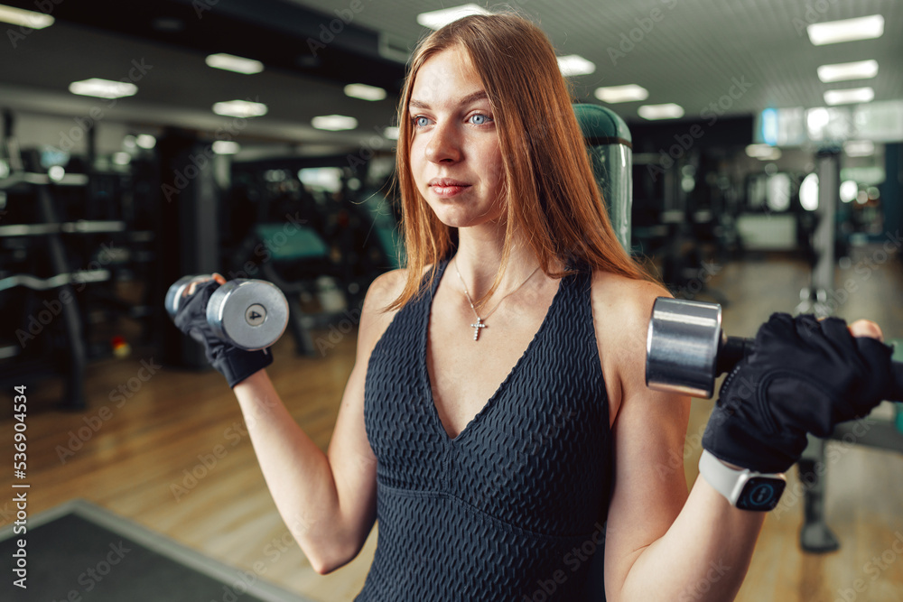 Fototapeta premium Smiling teen girl training in a fitness club