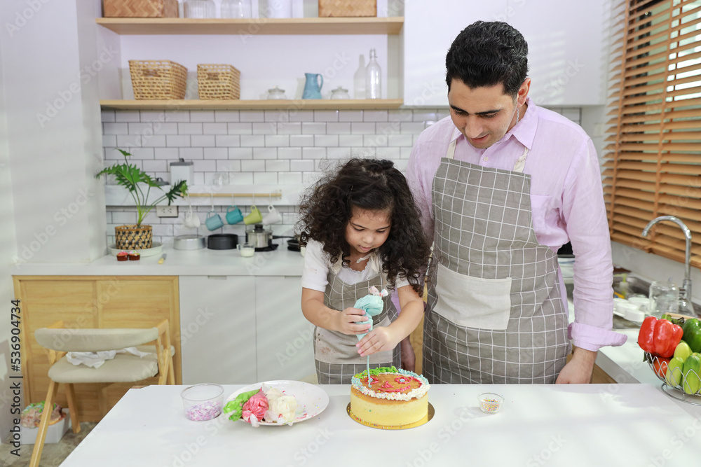 Happy lovely asian single dad and cute daughter in apron having fun with teaching and decorating homemade cake in the kitchen. Family lifestyle cooking with education concept. Happy lovely asian single dad and cute daughter in apron having fun with teaching and decorating homemade cake in the kitchen. Family lifestyle cooking with education concept.