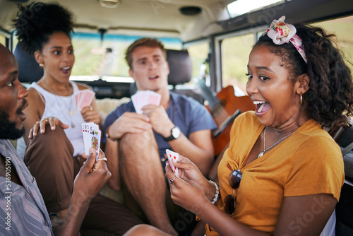 Playing cards, road trip and friends in van winning and excited for adventure journey, holiday and youth games lifestyle. Diversity group of people, camping and winner with card game in a caravan car