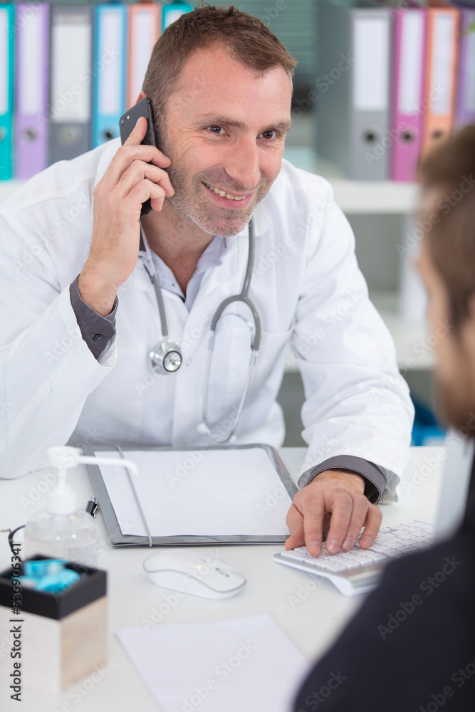 Fototapeta premium male doctor using telephone during consultation with patient