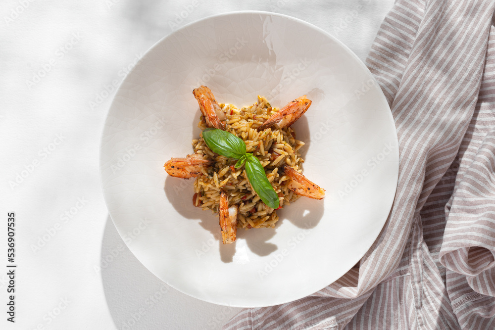 Orzo pasta with shrimps on white background for restaurant menu. Flat lay.