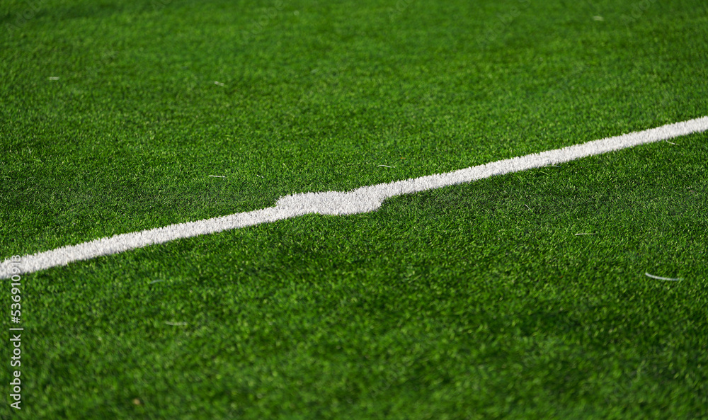 Close up detail field of the artificial grass from a brand new soccer field, view with the white marking line.