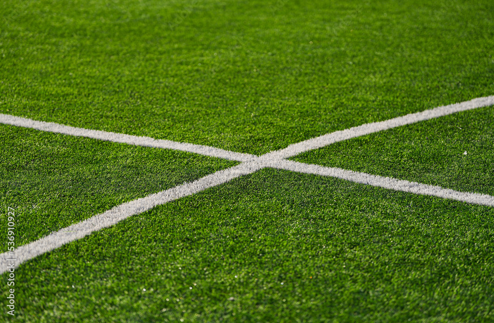 Close up detail field of the artificial grass from a brand new soccer field, view with the white marking line.