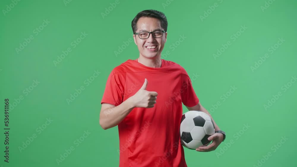 Asian Man With A Ball Showing Thumbs Up Gesture While Cheering Soccer On Green Screen Background
Asian Man With A Ball Showing Thumbs Up Gesture While Cheering Soccer On Green Screen Background
