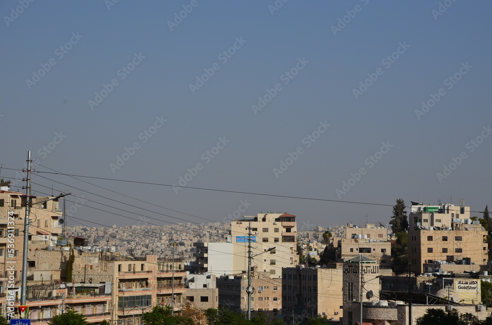The chaotic city of Amman with its tanks, buildings and architecture on a bright sunny day with a clear sky.
