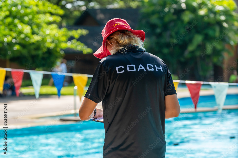 Naklejka premium Back view of swimming coaches, wearing COACH shirt