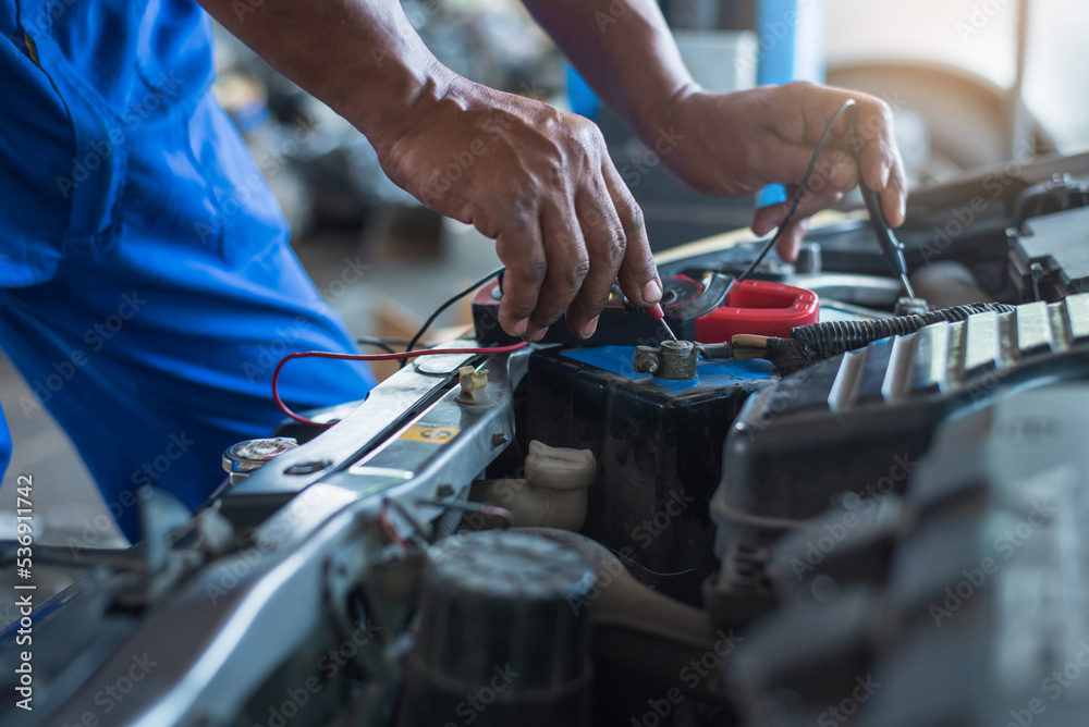 Auto mechanics use a multimeter voltmeter to measure the voltage in the car battery. Auto mechanics use a multimeter voltmeter to measure the voltage in the car battery.