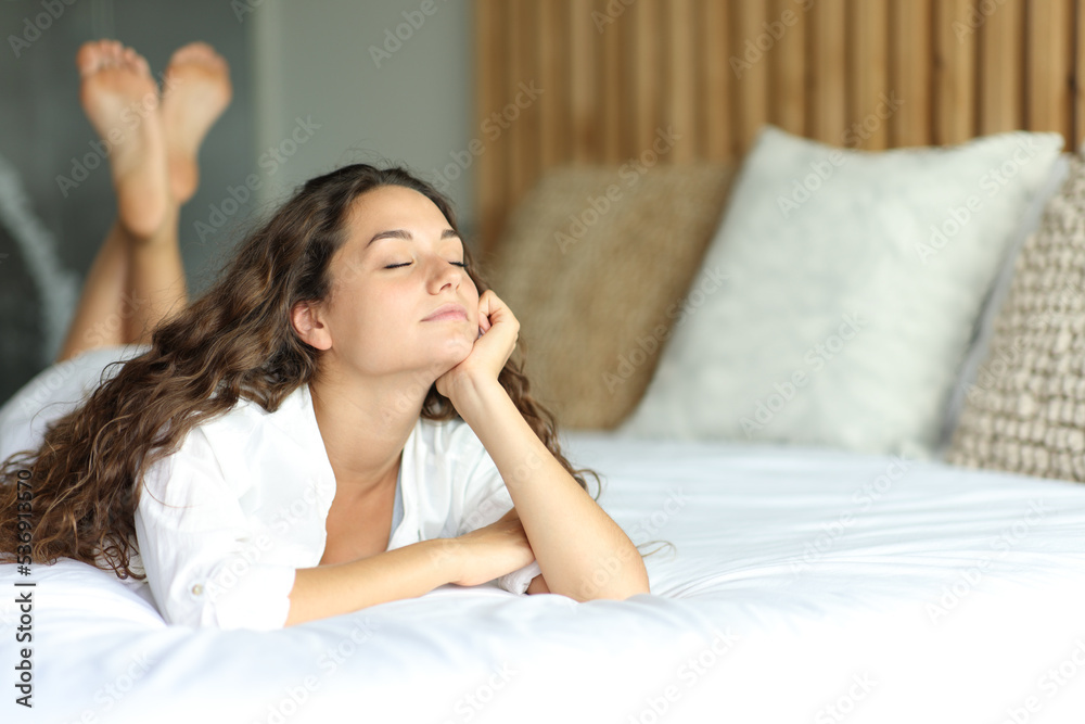 Relaxed woman resting on a bed in a hotel room Relaxed woman resting on a bed in a hotel room