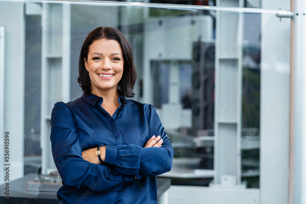 Smiling businesswoman with arms crossed in industry Smiling businesswoman with arms crossed in industry