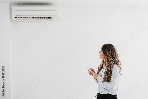 Businesswoman switching on air conditioning in the office