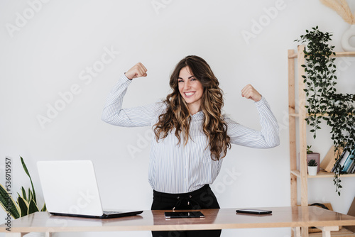 Strong businesswoman flexing muscles in office