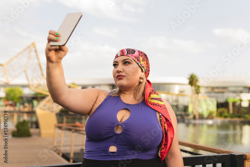 Woman wearing headscarf taking selfie through smart phone