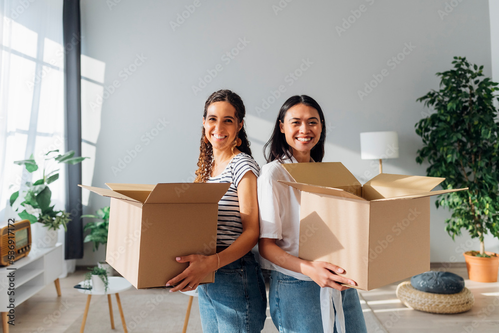Smiling friends with cardboard boxes moving in new house Smiling friends with cardboard boxes moving in new house