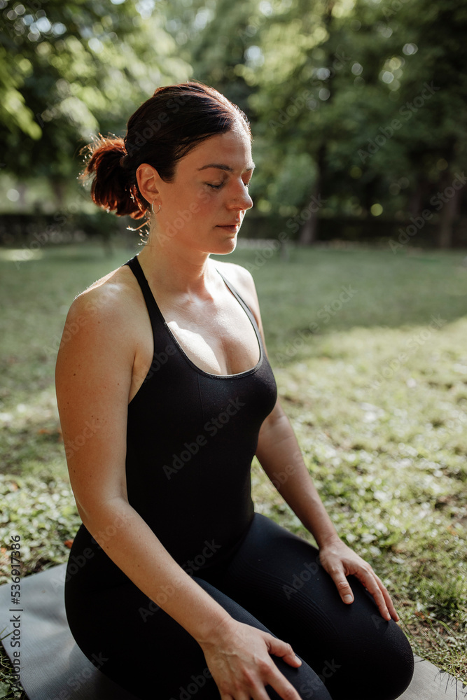 Yoga teacher with eyes closed on exercise mat in park Yoga teacher with eyes closed on exercise mat in park
