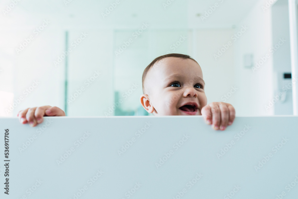 Happy cute boy playing in white crib Happy cute boy playing in white crib