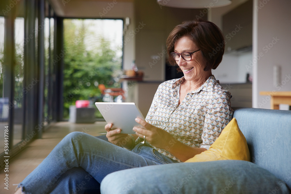 Happy senior woman using tablet PC on sofa at home Happy senior woman using tablet PC on sofa at home