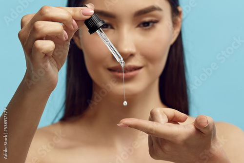 Portrait of pretty woman dripping serum on her finger. photo