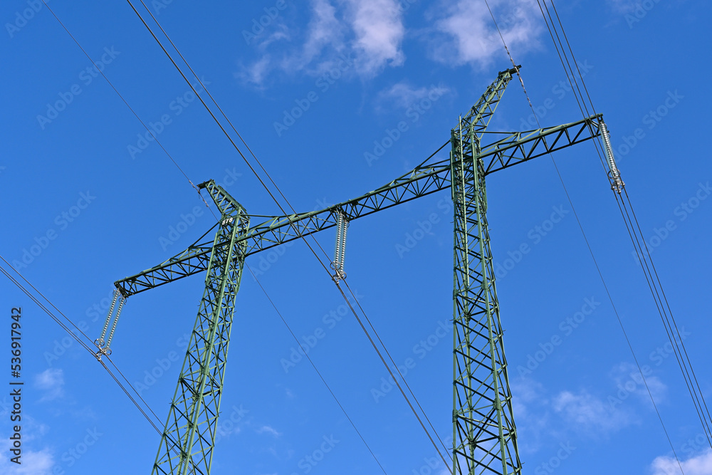 Pylons for high voltage transmission line. View from underside to masts and blue sky.