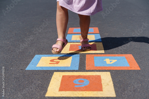 Girl playing hopscotch on footpath with numbers photo