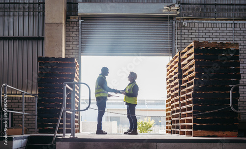 Happy logistics partners shaking hands at a loading dock photo