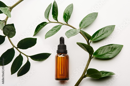 Amber dropper bottle lying inside floral branches.