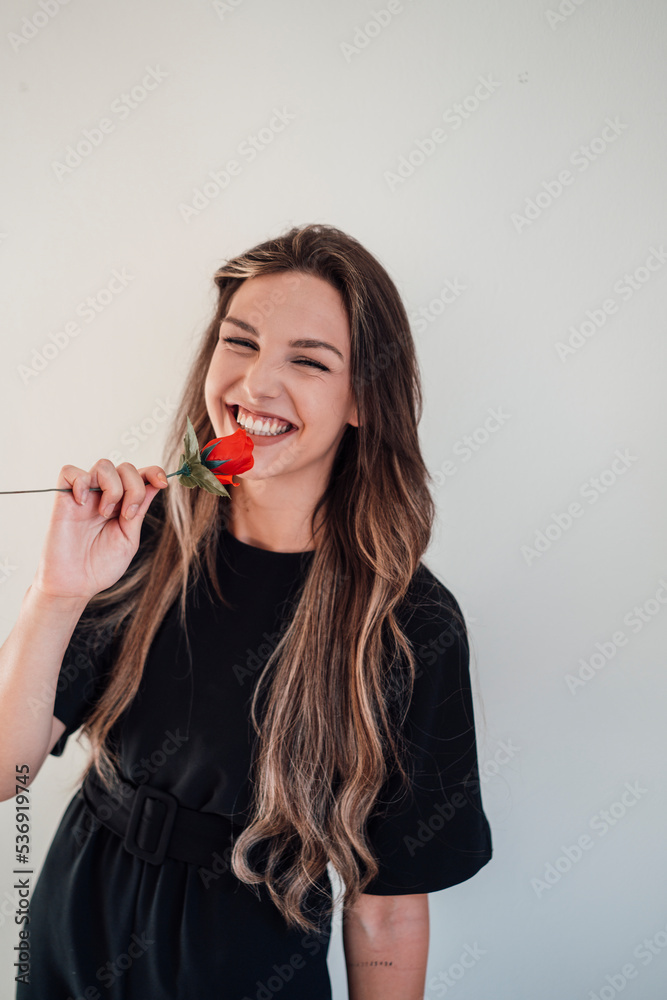 Cheerful young woman having fun with red rose against white background Cheerful young woman having fun with red rose against white background