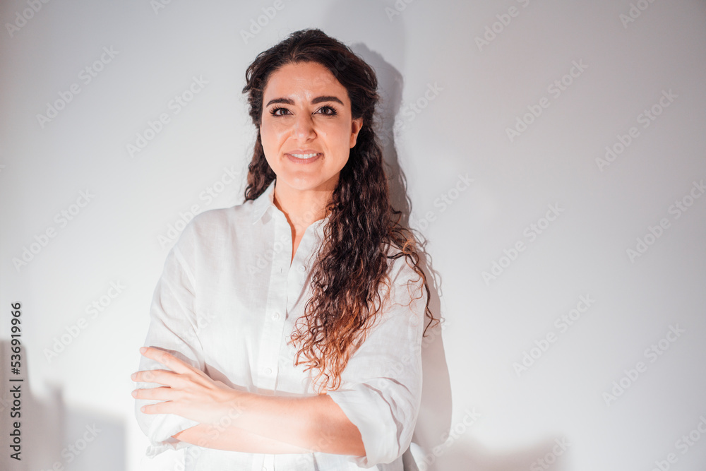 Smiling woman with arms crossed in front of wall at home Smiling woman with arms crossed in front of wall at home