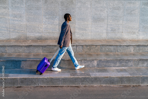 Smiling businessman with suitcase walking on step