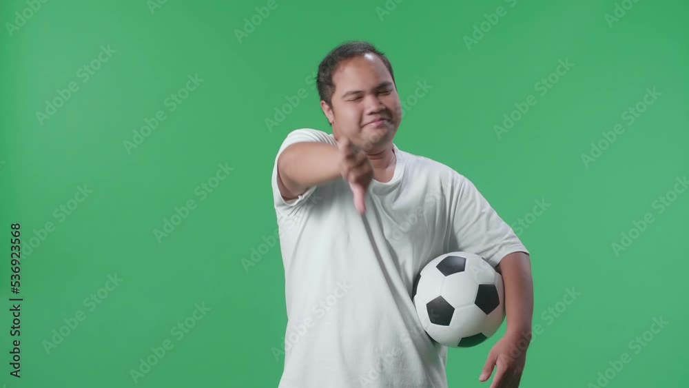 Asian Man With A Ball Showing Thumbs Down Gesture For Making Fun Of The Losers While Cheering Soccer On Green Screen Background
Asian Man With A Ball Showing Thumbs Down Gesture For Making Fun Of The Losers While Cheering Soccer On Green Screen Background