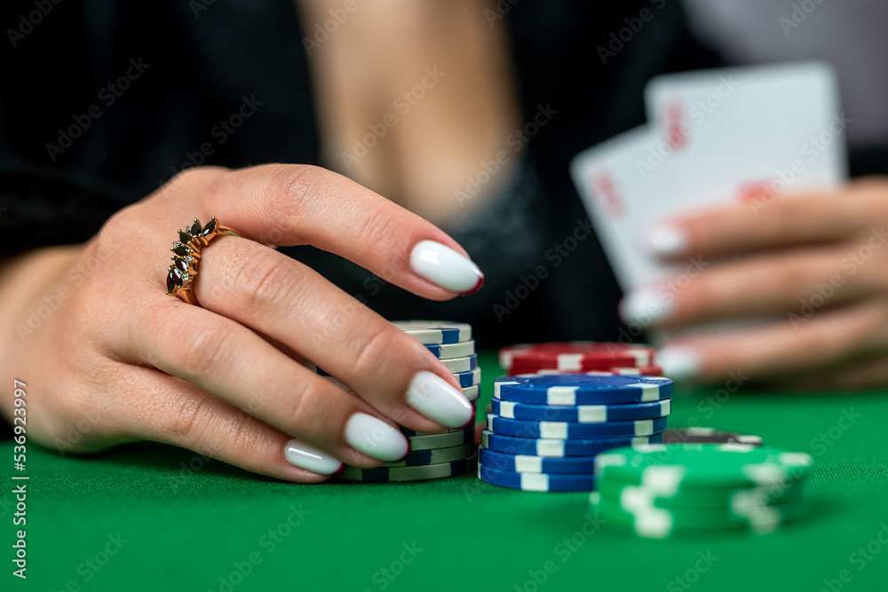 beautiful woman in an evening black dress plays poker in a casino at a green table. beautiful woman in an evening black dress plays poker in a casino at a green table.