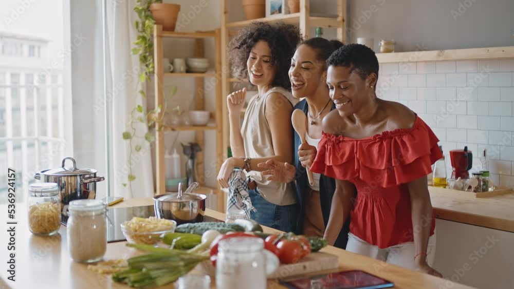 Beautiful young women spending time together and having fun. Latin and hispanic girls lifestyle moments in the kitchen while cooking. Representation of happy friends laughing and sharing good vibes