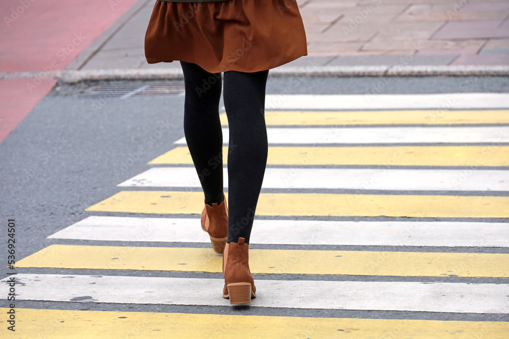 Female legs in black warm tights and brown shoes on pedestrian