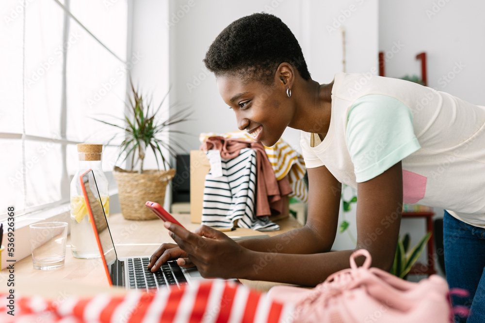 © Xavier Lorenzo - Smiling small business african owner woman with mobile phone using laptop in office - Happy millennial business woman working at store workplace © Xavier Lorenzo - Smiling small business african owner woman with mobile phone using laptop in office - Happy millennial business woman working at store workplace