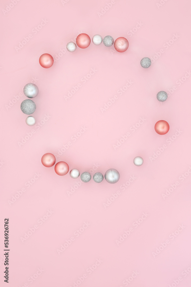 Abstract festive Christmas wreath with tree bauble ornaments on pastel pink background. Design composition for winter Xmas and New Year.